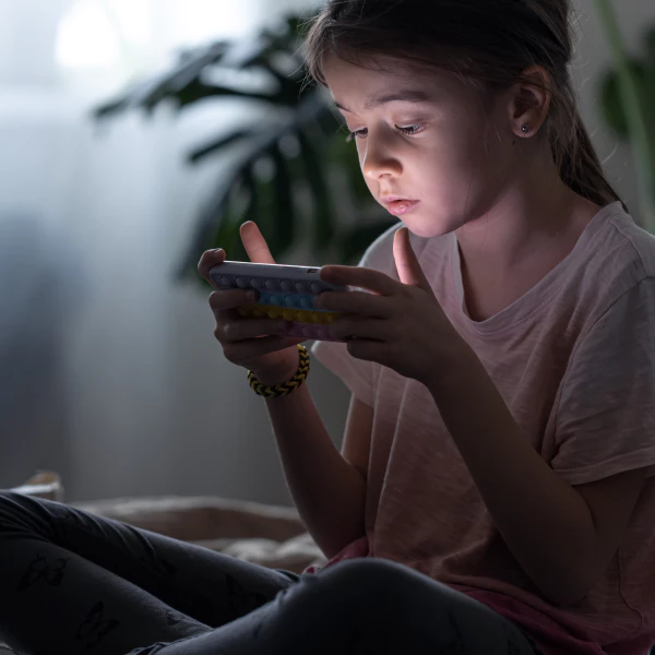 Ein kleines Mädchen, das auf einem Telefon Inhalte ab 18 Jahren durchstöbert